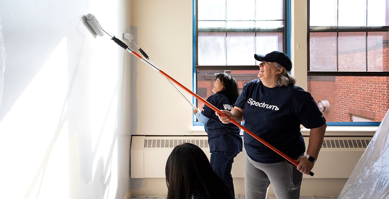 Two female volunteers painting a wall inside a community center